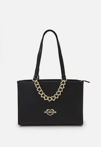 Svart tote-väska i syntetiskt material, med en geometrisk kedjedetalj i guldton och logotypdetalj på framsidan. Dragkedjestängning högst upp.