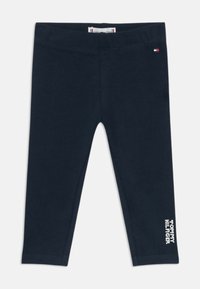 Jūros laivyno leggings, pagaminti iš minkštos medvilnės, su siūtu juosmeniu ir balto teksto grafika kairėje kojoje. Be raštų ar detalės.