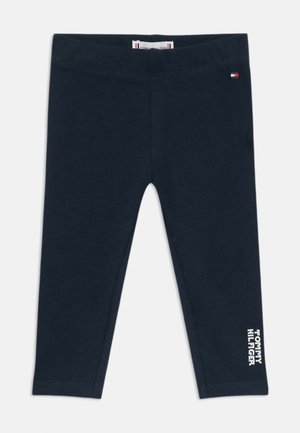 Mørkeblå leggings i blødt bomuldsstof med en syet talje og en hvid tekstgrafik på venstre ben. Ingen mønstre eller hardware.