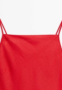 Rotes ärmelloses Kleidungsstück mit dünnen doppelten Schulterriemen und geradem Ausschnitt, hergestellt aus strukturiertem Stoff.