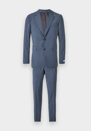 Costum bleumarin închis cu rever ascuțit, două nasturi și buzunare frontale. Croială ajustată, țesătură texturată și pantaloni asortați cu detalii de pliu.
