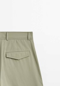 Shorts vert clair avec une texture lisse, dotés d'une taille droite, de deux passants de ceinture et d'une poche arrière avec un détail de coutures droites.
