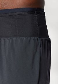 Schwarze Schwimmshorts mit einem strukturierten Bund und glattem unteren Abschnitt aus Stoff. Sie verfügen über einen elastischen Bund und eine geraffte Detail am Saum.