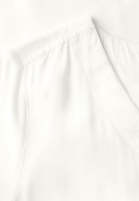 Top bianco a maniche corte con scollatura a V. Tessuto morbido, design semplice e dettagli di cucitura su misura lungo la cucitura della spalla.