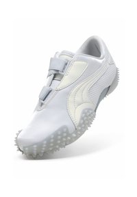 Chaussure de sport blanche avec semelle à adhérence texturée, deux bandes auto-agrippantes et panneaux en maille pour la ventilation, présentée de biais pour montrer le côté extérieur et la semelle.