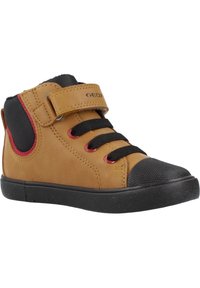 Hnědá kožená vysoká bota s černou gumovou podrážkou, černými tkaničkami, červenými očky a suchým zipem. Má texturované panely po stranách.