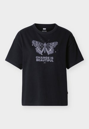 Μαύρο T-shirt με μεγάλο γραφικό σχέδιο πεταλούδας και παγιέτες πάνω από το κείμενο «Η ΑΛΛΑΓΗ ΕΙΝΑΙ ΟΜΟΡΦΗ» με έντονα γράμματα στο μπροστινό μέρος.
