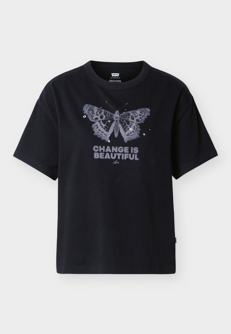 T-shirt noir avec un grand motif de papillon et des paillettes au-dessus du texte « LE CHANGEMENT EST BEAU » en lettres majuscules sur le devant.