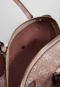 Różowa skórzana torebka od wewnątrz z zamkiem błyskawicznym, z gładką, teksturowaną podszewką i wytłoczonym wzorem logo. Posiada metalowy zatrzask.