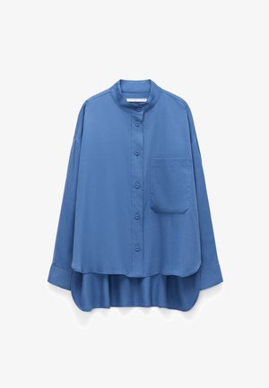 Niebieska koszula na długi rękaw zapinana na guziki, z kołnierzem typu mandarynka, pojedynczą kieszenią na piersi oraz zaokrąglonym, przedłużonym do tyłu dołem.
