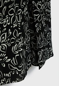 Schwarzer Stoff mit einem weißen Blumenmuster, das verschiedene Blätter und Blüten zeigt. Glatte Textur mit einem dezenten Glanz, leicht fließendes Design.