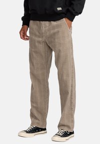 Beige geruite broek gemaakt van textuurstof, met zijzakken en een recht model, gecombineerd met zwarte lage sneakers.