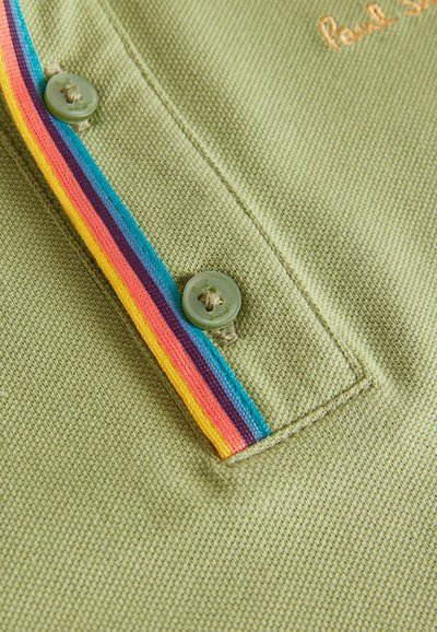 Polo verde con tessuto testurizzato, striscia multicolore e chiusura a bottoni. Nome del brand ricamato in arancione.