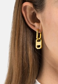 Orecchini a forma di lucchetto dorato con superficie texturizzata e attacco ad anello liscio. Il design leggero migliora l'appeal visivo.