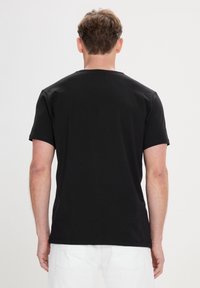 Sort kortærmet t-shirt lavet af et glat bomuldsmateriale, med en klassisk rund halsudskæring og en afslappet pasform, vist fra ryggen.