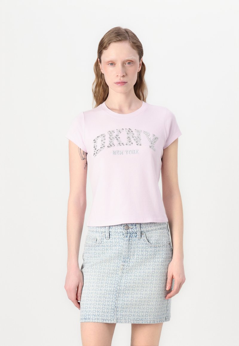 Púder rózsaszín, rövid ujjú póló, ezüst strasszkövekkel a "DKNY NEW YORK" felirattal. Farmer szoknyával párosítva, amely kék mintás dizájnnal rendelkezik.