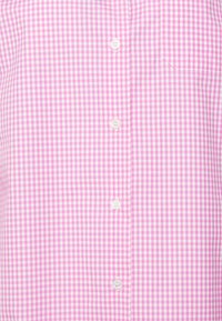 Różowo-biały koszulowy T-shirt w kratkę z kieszenią na piersi, z białymi guzikami i gładkim bawełnianym materiałem.