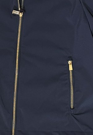 Tessuto blu navy con due cerniere verticali dorate, una più grande con linguetta di scorrimento e una più piccola per una tasca.