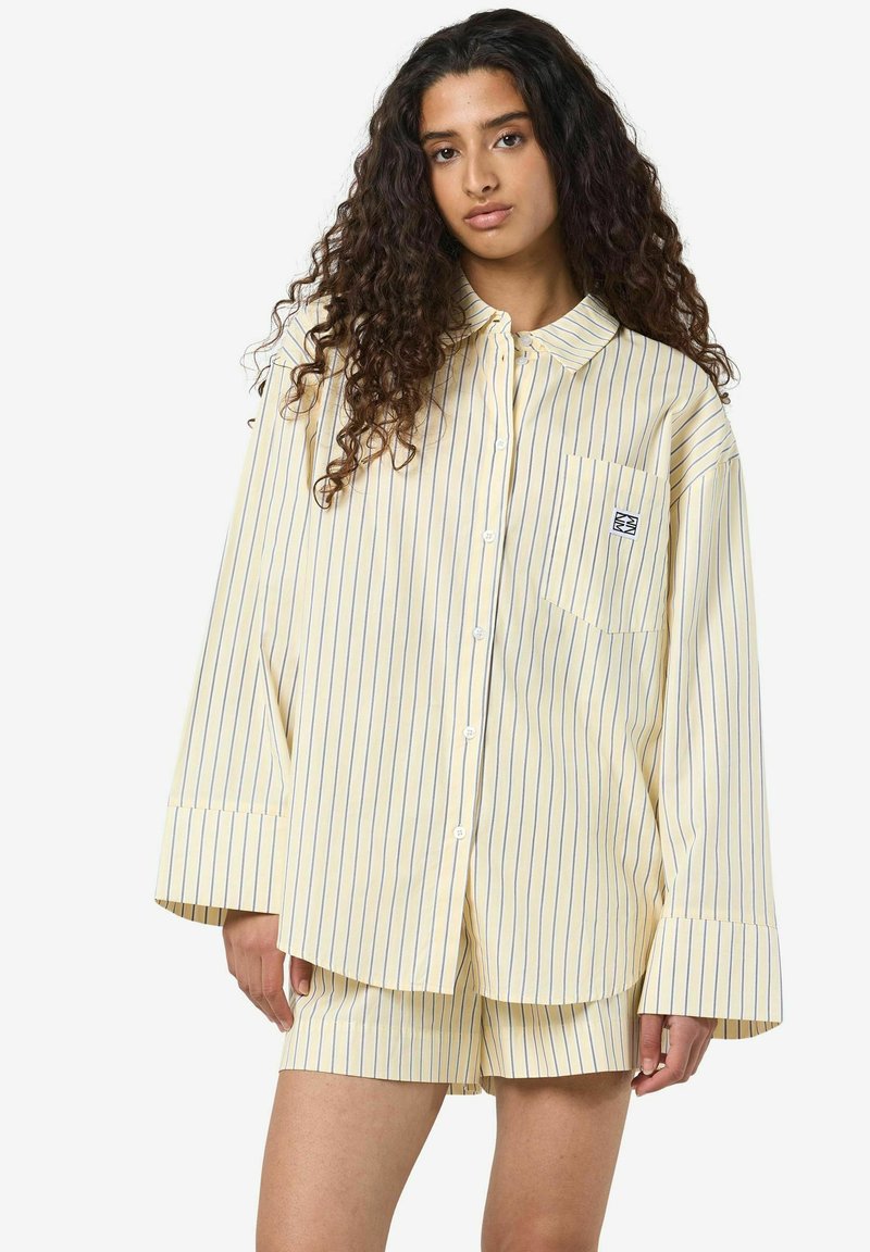 Ribad kollane särg pikkade varukatega, nupuga ees ja rinnataskuga; koos sobivate ribadega lühikeste pükstega; puuvillane kangas.