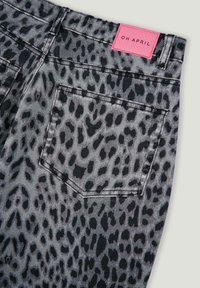 Shorts di denim grigio con un motivo a stampa leopardata nera, con un'etichetta rosa "OH APRIL" e una tasca posteriore.