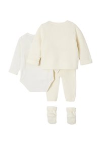 Cremefarbenes Babykleidungsset mit geripptem Pullover, Hose, Handschuhen und einem Langarm-Body, flach auf einem weißen Hintergrund ausgelegt.