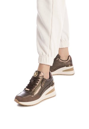 Zapatillas metálicas marrones con tacón grueso, que cuentan con cierre con cordones, cremallera lateral y paneles de ante texturizados. La suela blanca añade contraste.