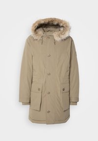 Beige parka takki, jossa on tekokarvavilla reunus hupussa, etuvetoketju ja napitus, kaksi suurta etutaskua ja joustavat hihansuut. Pehmeä, teksturoitu kangas.