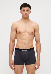 Schwarze BOSS Boxer-Shorts mit logoziertem Bund, aus glattem Material gefertigt, mit passgenauer Silhouette und mittellanger Beinlänge.