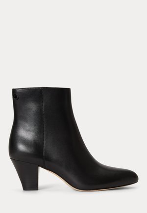 Bottine noire en cuir avec un petit talon carré et un bout pointu, vue de profil sur fond uni.