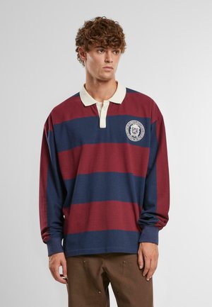 Koszulka polo z długim rękawem w bordowe i granatowe paski. Posiada kremowy kołnierzyk oraz okrągłe logo po lewej stronie na klatce piersiowej. Wykonana z miękkiej bawełny.