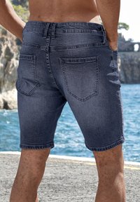 Denim shorts in dark blue with a fitted design. Features include back pockets, stitched seams, and a slightly frayed hem.