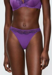 Bikini w fioletowymi koronkowymi wykończeniami, charakteryzujący się gładką teksturą i niskim stanem, z misternymi detalami wzdłuż pasa i miseczki.
