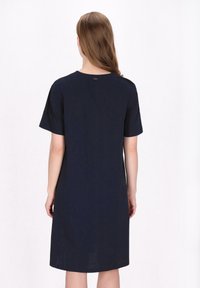 Marineblaues, locker sitzendes Kleid mit kurzen Ärmeln, rundem Halsausschnitt und weicher Textur. Einfaches Design, knielang, minimalistische Details.
