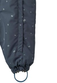 Materiał kurtki przeciwwiatrowej w ciemnoniebieskim kolorze z subtelnym wzorem jasnoszarych liter. Posiada elastyczny mankiet ze sznurkiem do regulacji i pewnego dopasowania.