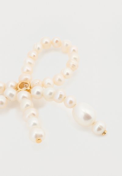 Pulsera de perlas con perlas blancas de tamaños variados, con una textura suave; asegurada con un cierre de oro en el centro.