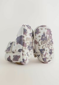 Stivaletti morbidi in suede con una base bianca, caratterizzati da un motivo astratto in viola e beige. Include una fascia per una chiusura sicura e dettagli testuali.