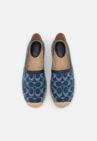 Denim espadriller med ett blått cirkulärt mönster, rund tå, svart kant och vävd jutesula, med en texturerad inredning.