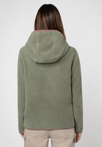 Fleecejacke in olivgrün, mit einer großen Kapuze, weichem Material und kontrastierenden burgunderfarbenen Abschlüssen an Saum und Bündchen.