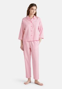 Roze gestreepte pyjama set met een knoopsluiting bovenstuk met een kraag en driekwart mouwen, gecombineerd met bijpassende broek met opgerolde manchetten.