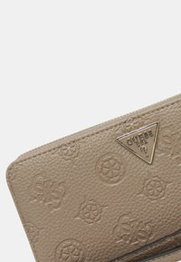 Portafoglio beige testurizzato con motivi a logo in rilievo, dotato di un emblema metallico triangolare del marchio e di una chiusura con zip.