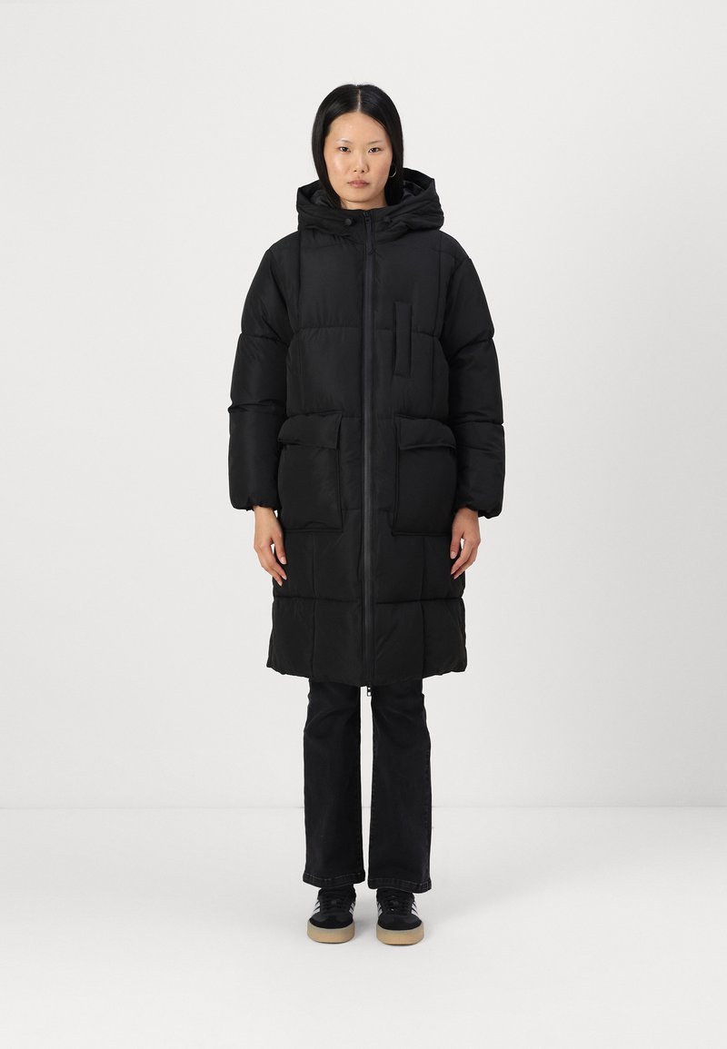 Mustat, polvipituiset toppatakki huppulla, etuvetoketjulla, kaksi suurta etutaskua ja rintatasku. Pehmeä rakenne ja paksu eristys.