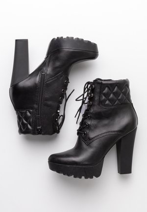 Paire de bottines à talons hauts en cuir noir avec lacets à l'avant, fermetures éclair latérales, cols matelassés et semelles épaisses à crampons.