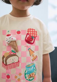 Crèmewitte katoenen t-shirt met een kleurrijk, speels voedselgrafiek ontwerp. Belangrijke details zijn onder andere ijsjes, aardbeien en een geruit patroon.
