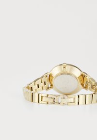 Montre en métal doré avec un bracelet à maillons, boîtier rond et dos lisse. Présente un cadran simple avec peu de détails.