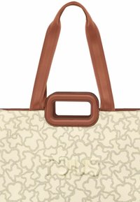 Bolso tote beige con un patrón abstracto texturizado, que presenta correas de tela marrones y un detalle de asa rectangular. Logo sutilmente grabado visible.