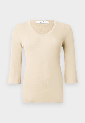 Bež ribaga pikendatud varrukatega tipp, millel on laia kaelusega lõik. Tekstuur on sile ja keha lähedal. Laienevad mansetid lisavad õrna disainielementi.