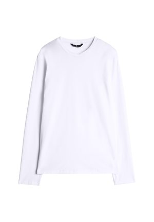 Maglietta bianca a maniche lunghe con scollo rotondo, distesa su uno sfondo bianco con un'etichetta nera all'interno del colletto.