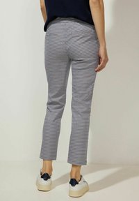 Kalhoty s kostkovaným vzorem v námořnické modři a bílé, slim fit, zkrácené délky s zadními kapsami, spárované s bílými teniskami s námořnickými akcenty.