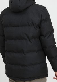 Sort pufferjakke i syntetisk materiale, quiltet design, hætte og elastiske manchetter. Glat tekstur med en strømlinet silhuet.