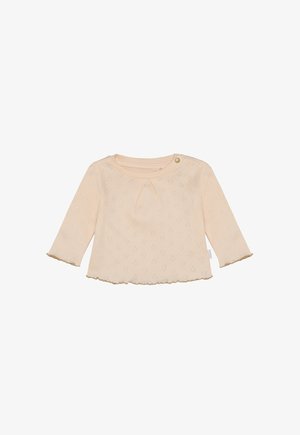 Hell pfirsichfarbener Langarm-Top mit rundem Ausschnitt, strukturiertem Herzmuster und gewelltem Saum. Abgeschlossen mit einem kleinen goldenen Knopfdetail.